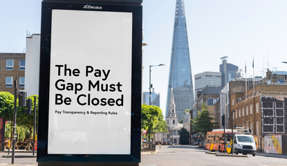 Billboard reading “The pay gap must be closed” with The Shard and city skyline, London, UK