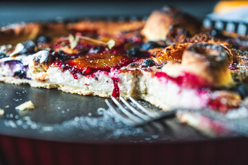 A delicious berry dessert, a piece of tart or an open sweet pie with figs, blueberries and apricots on a black plate. High quality photo