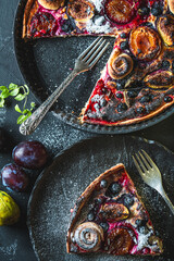 A delicious berry dessert, a piece of tart or an open sweet pie with figs, blueberries and apricots on a black plate. High quality photo