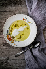 Creamy Green Vegetable Soup with Herb Oil in Vintage Bowl on a rustic table