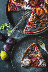 A delicious berry dessert, a piece of tart or an open sweet pie with figs, blueberries and apricots on a black plate. High quality photo