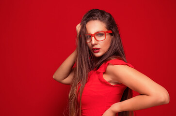 Serious young woman standing with neutral face expression, isolated on red background. Pretty girl.