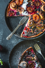 A delicious berry dessert, a piece of tart or an open sweet pie with figs, blueberries and apricots on a black plate. High quality photo