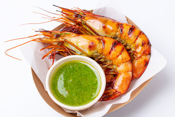 Boiled shrimp served in a takeout box with spicy green seafood dipping sauce. Isolated on white background, highlighting the fresh prawns, vibrant sauce, and glossy texture, Grilled prawn in carton 
