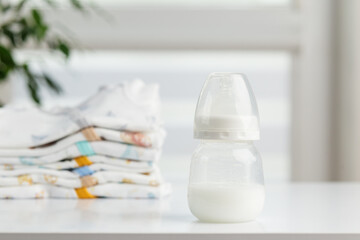 Baby milk bottle with folded clothes on table