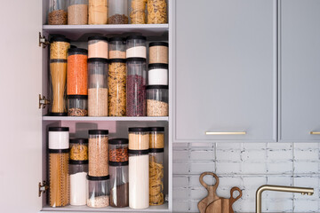 Organized kitchen pantry with cylindrical plastic jar for storing loose products,  in grey tones