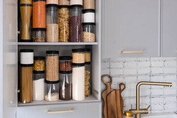 Organized kitchen pantry with cylindrical plastic jar for storing loose products,  in grey tones
