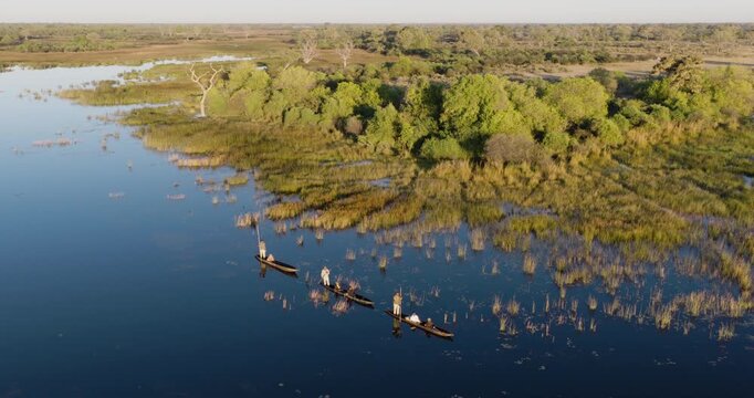 High aerial panning. Tourists enjoying a Mokoro safari on the waterways of the Okavango Delta  