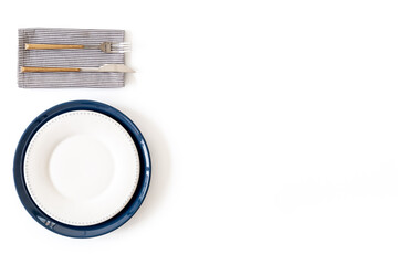 Top view of minimalistic table setting with empty plate, cutlery and napkin on white background,...