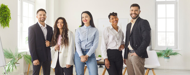 Group of smiling diverse business professionals standing together in modern office space....
