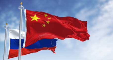 The flags of China and Russia waving in the wind on a clear day