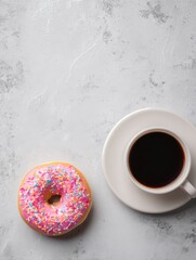 A delectable pink frosted donut with colorful sprinkles sits next to a cup of black coffee on a smooth gray surface, offering a perfect breakfast treat to start the day
