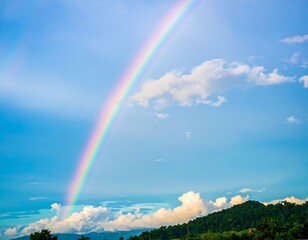 A stunning rainbow gracefully arches across a vibrant blue sky landscape