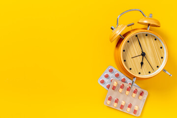 Medical treatment pills and vintage alarm clock, top view. Time to take medicine concept