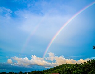A Vivid Double Rainbow Arcs Across a Serene Sky Over Lush Greenery