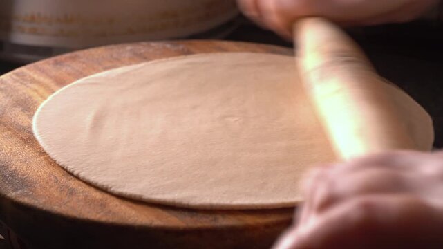 Close-up of a woman hand making Indian roti or chapati at home. Traditional flatbread preparation at  kitchen