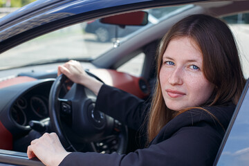 Naklejka premium Portrait of a smiling young woman sitting in a car. Car rental and sale.