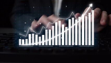 A focused business person analyzes a financial growth chart on a digital screen, showcasing data that represents success, trends, and technology in a professional environment. Copula