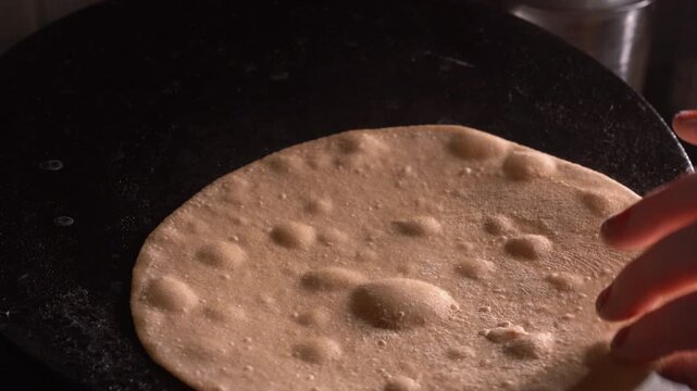 Close-up of a woman hand making Indian roti or chapati at home. Traditional flatbread preparation at  kitchen