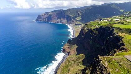 Fototapeta premium High-angle view of dramatic coastal cliffs, a dark sandy beach, and a vibrant blue ocean.