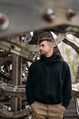 Portrait of a person in dark clothing among the rings and bolts of the Universal Mind sculpture in Nikola-Lenivets park, metal and wood textures, daylight, creative art, abstract structure, modern moo