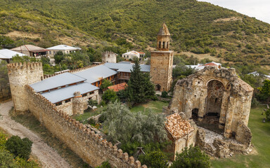 Drone view of Ninotsminda Cathedral complex with medieval stone walls, bell tower, and church ruins