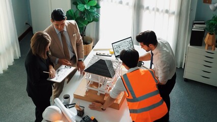 Top view of professional architect engineer team inspect house model while manager holding blueprint and asking about building construction. Group of diverse engineer working together. Alimentation.
