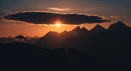 Dramatic sunset over mountain range with solitary tree on horizon