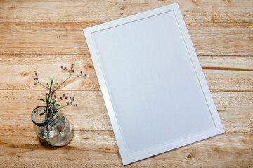 Blank White Frame with Flowers on a Wooden Table