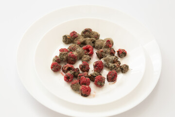 Close-up of moldy raspberries on a white plate, symbolizing decay and food spoilage.