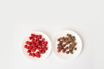 Two plates side by side: fresh raspberries and moldy raspberries, top view on white background.