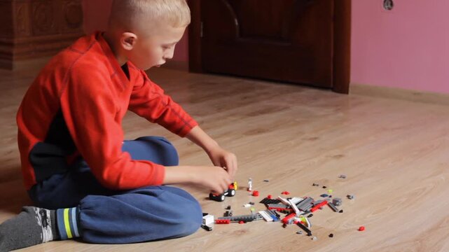 boy plays with toys on the floor, boy in the room on the floor plays with a toy constructor