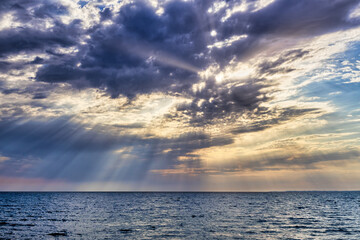 Obraz premium Sunbeams Breaking Through a Dramatic and Cloudy Sky Over the Sea