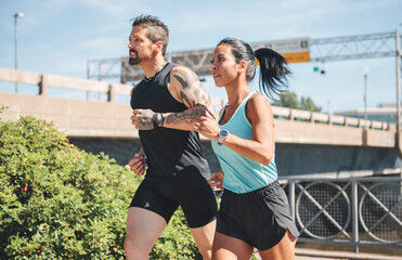 Young fitness couple running on a city on summer day
