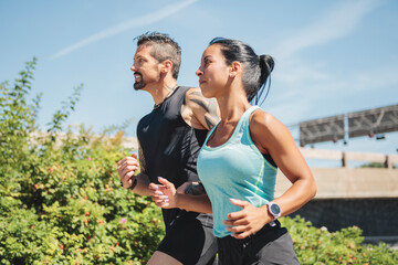 Young fitness couple running on a city on summer day