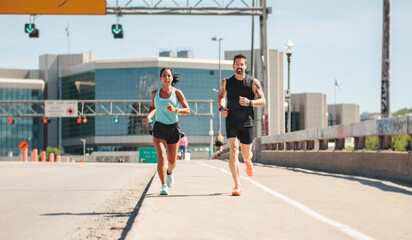 Young fitness couple running on a city on summer day