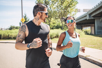 Young fitness couple running on a city on summer day
