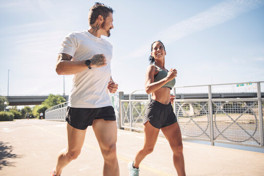 Young fitness couple running on a city on summer day - Powered by Adobe
