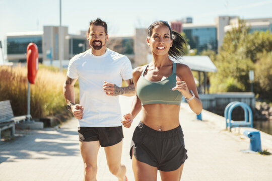 Young fitness couple running on a city on summer day