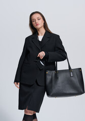 Girl model in stylish clothes with bag posing in studio