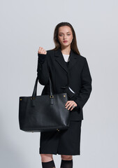 Girl model in stylish clothes with bag posing in studio