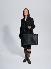 Girl model in stylish clothes with bag posing in studio