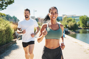 Young fitness couple running on a city on summer day