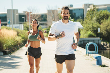 Young fitness couple running on a city on summer day
