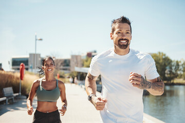 Young fitness couple running on a city on summer day