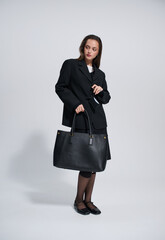 Girl model in stylish clothes with bag posing in studio