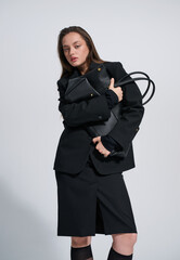 Girl model in stylish clothes with bag posing in studio