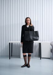 Girl model in stylish clothes with bag posing in studio