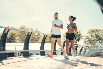 Young fitness couple running on a city on summer day