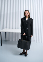 Girl model in stylish clothes with bag posing in studio